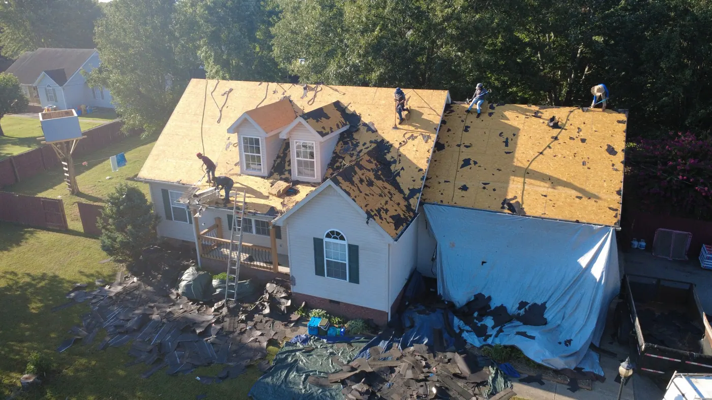 Roofing crew removing old shingles and exposing roof decking